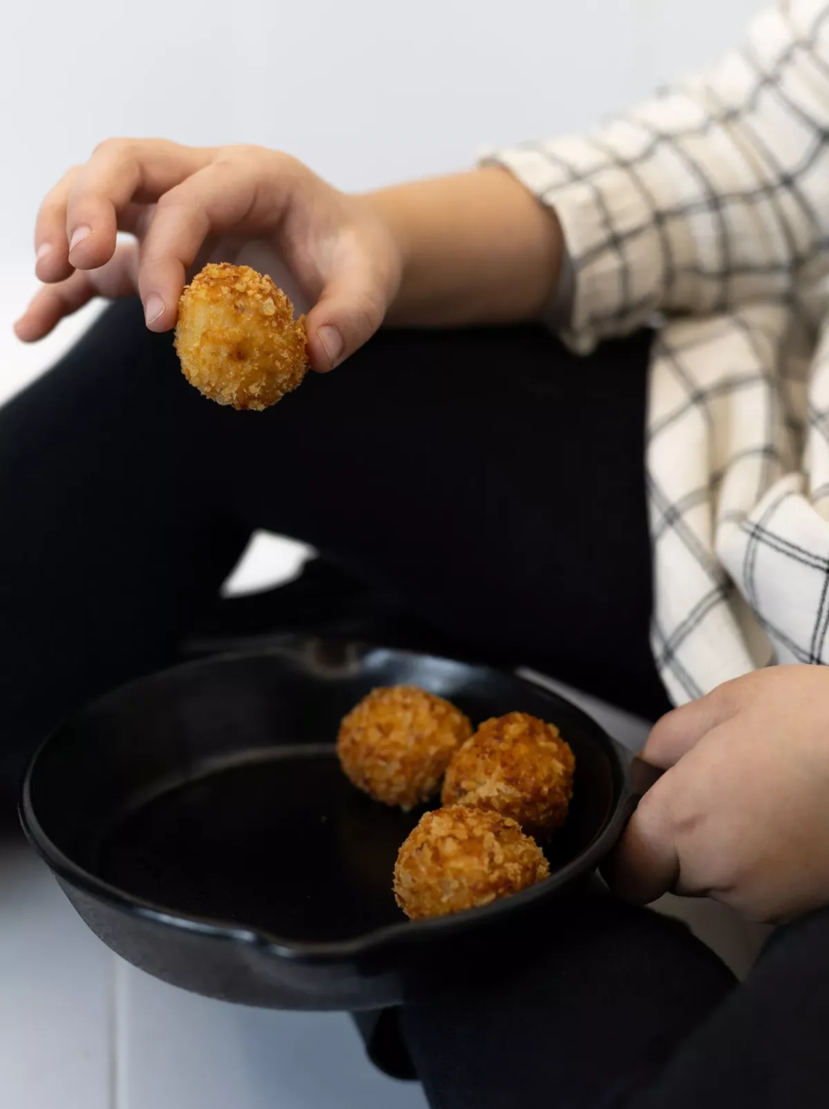 Persona con una croqueta en mano y otras en sartén.