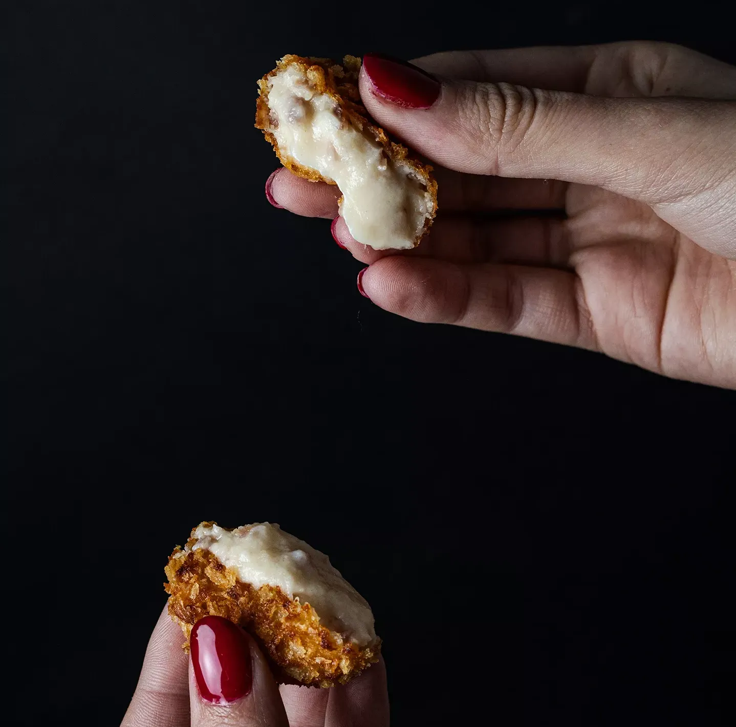Manos con croqueta partida para ver su relleno